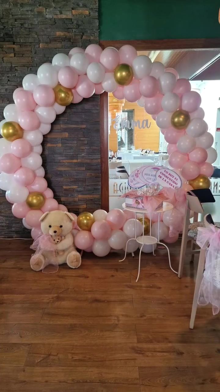 Arco de globos rosa y oro con osito en una comunión