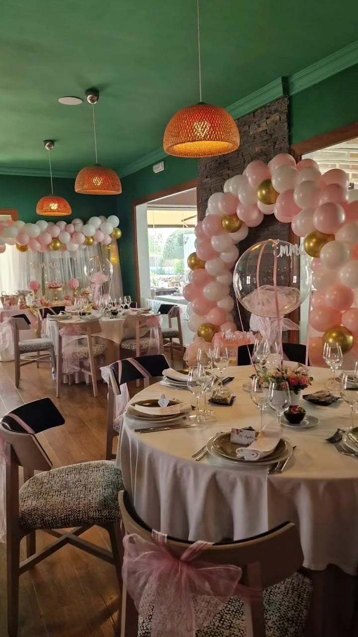 Salón de comunión decorado con globos y mesas vestidas de blanco